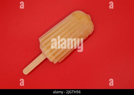 Pop cicle arancione isolato su sfondo rosso. Colori brillanti, atmosfera estiva Foto Stock