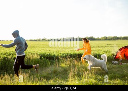 Le giovani coppie giocano con il loro cane al campeggio Foto Stock