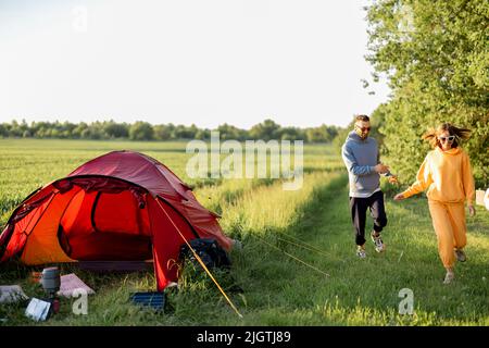 Le giovani coppie giocano con il loro cane al campeggio Foto Stock