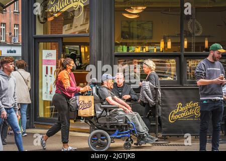 Uomo disabili su sedia a rotelle con accompagnatore di dama di fronte al bar. Dublino. Irlanda. Foto Stock