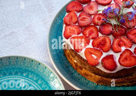 Torta con fragole e panna su piatto blu. Summer Strawberry e Crema spugnoso strato torta su sfondo bianco tavolo panno. Vista dall'alto, spazio di copia. Foto Stock