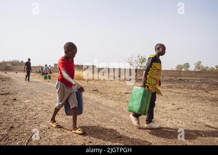 I bambini africani prelevano acqua da una pompa di villaggio; la mancanza di rubinetti e di lavoro minorile nei paesi in via di sviluppo Foto Stock