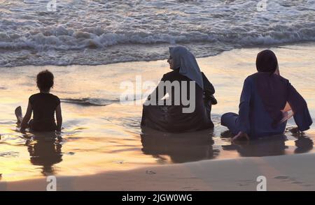 I palestinesi si riuniscono lungo la spiaggia durante la vacanza musulmana di Eid al-Adha il 11 luglio 2022 a Tel Aviv, Israele. Le autorità israeliane hanno permesso ai palestinesi della Cisgiordania di visitare Tel Aviv e altri luoghi in Israele durante le vacanze di Eid al-Adha. Foto Stock