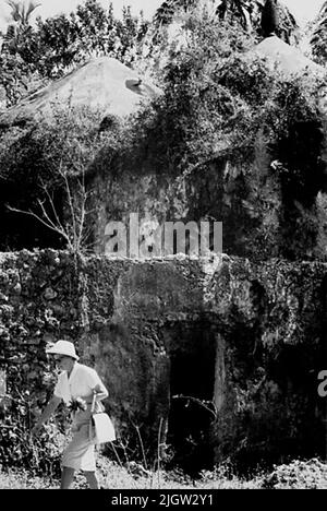 African journey, zanzibars acquisizione semplice: Libri e materiale di archivio.35 immagini in serie. La foto è stata scattata intorno al 1961-09-12. La moglie del fotografo si trova di fronte ad un edificio residenziale, che è in parte in crescita di cespugli e alberi. Foto Stock