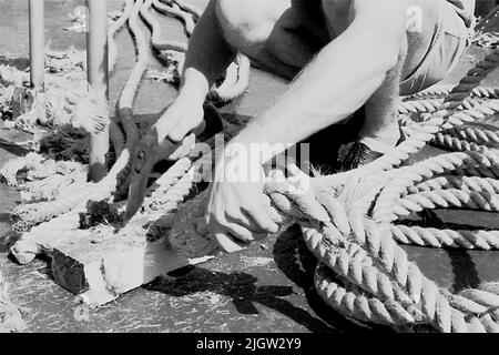La foto è stata scattata intorno al 1961-09-22. Un uomo siede su una nave. Ha strappato insieme treno. Ora taglia via l'abbondanza del treno con un'ascia. African travel35 immagini in serie. Foto Stock