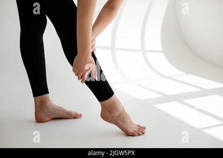 Ragazza in leggings neri che tiene la sua gamba Foto Stock
