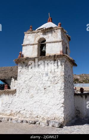 Il campanile in pietra della Chiesa della Vergine della Natività a Parinacota sull'altiplano andino in Cile. Parco Nazionale Lauca. Foto Stock
