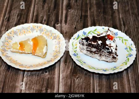 Un pezzo di torta della foresta nera a fette, un pan di Spagna al cioccolato con panna montata e ciliegie e una fetta di torta di frutta tropicale con gres Foto Stock