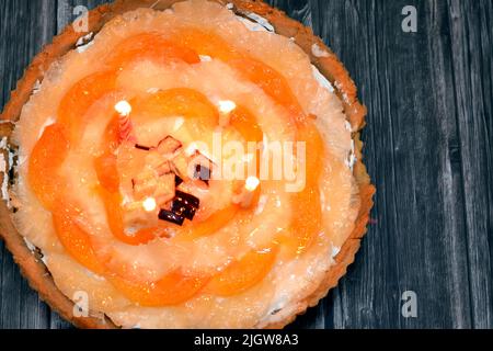 Una torta di frutta con candele di compleanno con pezzi freschi di mela, fette di spiaggia fresca e ananas con panna montata a base di un semplice Foto Stock