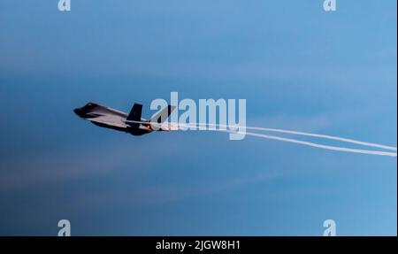 F-35 Lightning II Stealth aereo da combattimento multiruolo che vola con postbruciatori e lascia due piste di vapore fumogeno durante lo spettacolo aereo Foto Stock