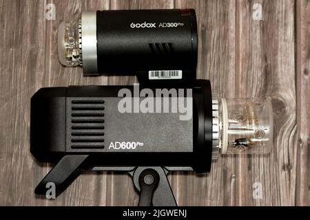 Cairo, Egitto, giugno 11 2022: Una testa flash portatile per esterni Godox AD600 Pro e Godox AD300 Pro con batterie agli ioni di litio isolate su uno sfondo di legno Foto Stock