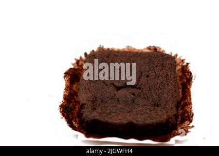 Dolce torta di cioccolato brownie pezzo isolato su uno sfondo bianco, fuoco selettivo di fetta di brownie con polvere di cacao su una carta di burro che è usuall Foto Stock