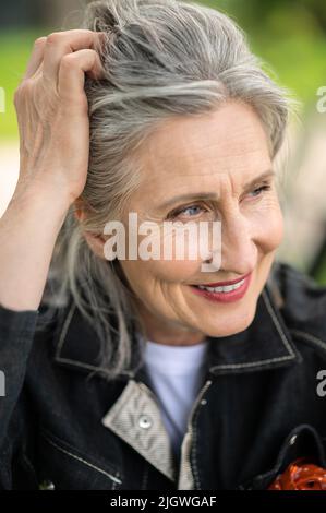 Ritratto di una donna matura sorridente e guardante da parte Foto Stock