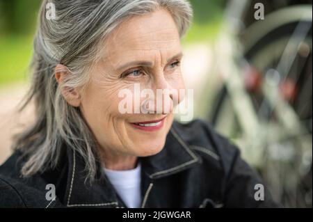 Ritratto di una donna matura sorridente e guardante da parte Foto Stock