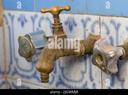 primo piano di vecchio rubinetto arrugginito e invecchiato su parete piastrellata Foto Stock