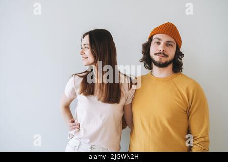 Ritratto di sorridente coppia giovane famiglia hippsters contro muro grigio Foto Stock