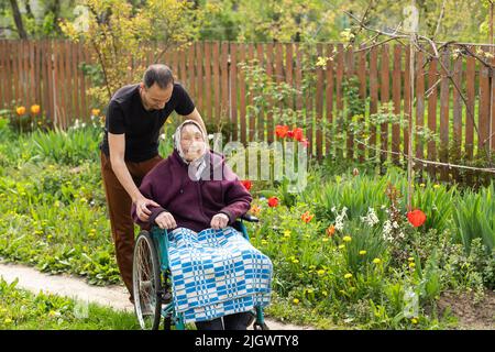 Assistente di cura senior con una donna disabile molto anziana in casa di cura. Foto Stock