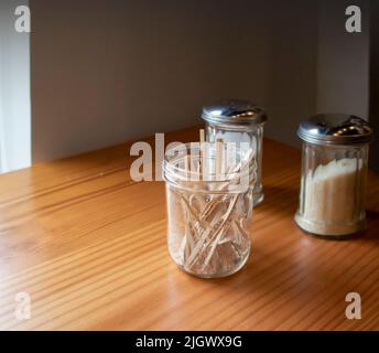 Dispenser di zucchero di canna e zucchero bianco e vasetto con bastoncini di legno per mescolare Foto Stock