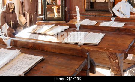 Imparare a leggere e scrivere nel concetto di mezza età. Un'aula con scrivanie in legno contenenti pergamena, rotoli, manoscritti e fontana di piume p Foto Stock