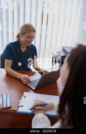 La paziente femminile scrive le raccomandazioni del medico durante l'appuntamento in clinica Foto Stock