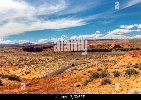 Le lunghe strade sul deserto vicino al fiume a Page, AZ, con la diga in fondo Foto Stock