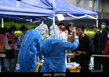 Shanghai, Cina-Marzo 24th 2022: Heath lavoratore che raccoglie campioni di tampone da residenti per test di acido nucleico nel distretto residenziale. Shanghai è in su Foto Stock