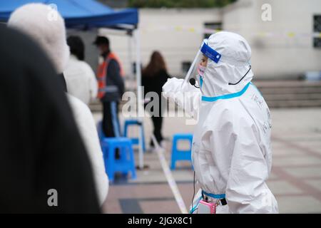 Shanghai,Cina-Marzo 19th 2022: L'operatore medico tiene l'ordine delle persone in fila per ricevere il test dell'acido nucleico per Covid-19 presso la comunità locale. Shanghai lo è Foto Stock