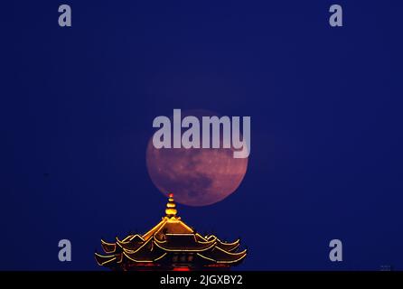 Wuhan, provincia cinese di Hubei. 13th luglio 2022. Una supermoon è raffigurata vicino alla Torre della Crane gialla a Wuhan, provincia centrale di Hubei, Cina, 13 luglio 2022. Credit: Zhou Guoqiang/Xinhua/Alamy Live News Foto Stock