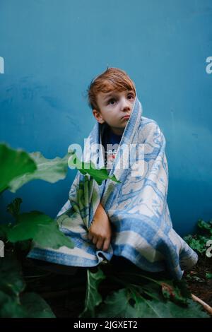 bambino triste con una faccia storta sotto le coperture Foto Stock