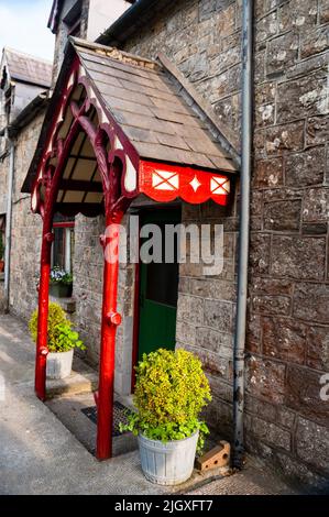 Colonne di ramo d'albero dipinte e bargeboard scolpito su cottage di pietra in Virginia, Irlanda. Foto Stock