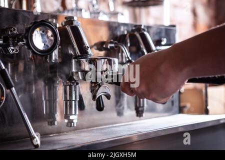 Chiusura del barista riscaldamento macchina per caffè espresso. Foto Stock