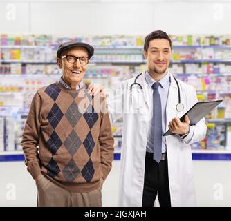 Chimico e un anziano paziente di sesso maschile in piedi in farmacia e guardando la macchina fotografica Foto Stock