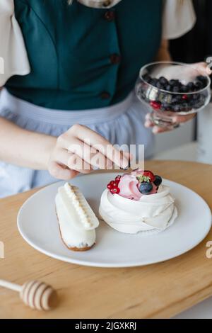 La pasticceria ragazza aggiunge una bacca alla torta Foto Stock