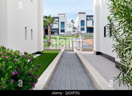 Uno stretto sentiero lungo due case bianche residenziali percorso che conduce al cortile interno di simili case cittadine Foto Stock
