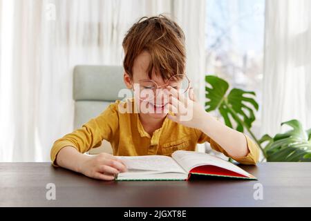 Ragazzo intelligente leggere libro e sorridente giorno Foto Stock