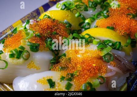 Un Ika Sushi da asporto (sushi di calamari) con Tobiko (Tobikko, uovo di pesce volante) e cipolla verde tritata in un vassoio Foto Stock