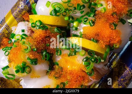 Un Ika Sushi da asporto (sushi di calamari) con Tobiko (Tobikko, uovo di pesce volante) e cipolla verde tritata in un vassoio Foto Stock