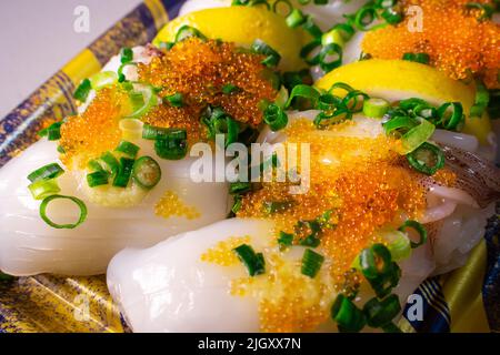 Un Ika Sushi da asporto (sushi di calamari) con Tobiko (Tobikko, uovo di pesce volante) e cipolla verde tritata in un vassoio Foto Stock