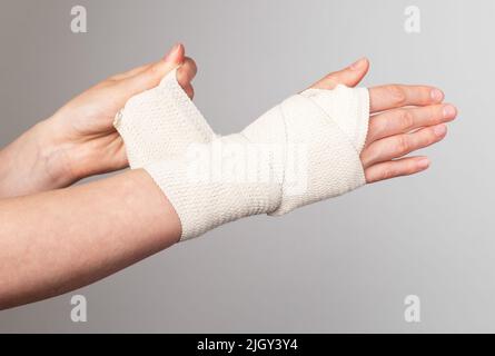 Donna che avvolge un bendaggio elastico intorno al polso doloroso. Avvolgimento a compressione. Distorsioni muscolari, trattamento di ceppi. Trauma del braccio. Concetto di assistenza sanitaria. Foto di alta qualità Foto Stock