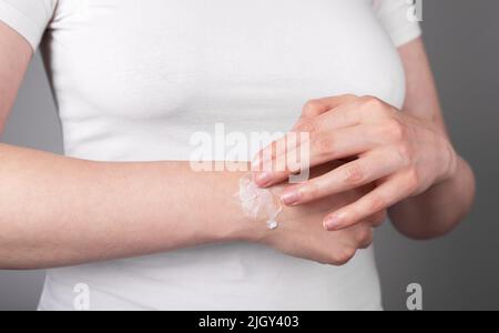 Donna che applica il gel di sollievo dal dolore sul polso spruzzato per gonfiore e riduzione dell'infiammazione. Lesione al braccio, malattia cronica. Concetto di assistenza sanitaria. Foto di alta qualità Foto Stock