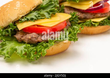 Burger Bun su foglia di lattuga con formaggio e pomodori. Primo piano. Sfondo bianco Foto Stock