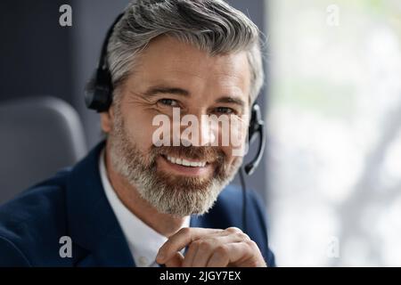 Servizio clienti. Ritratto di un bell'uomo di mezza età in cuffia e abito Foto Stock