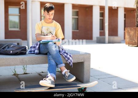 Ragazzo adolescente caucasico che fa i compiti prima di entrare nella scuola superiore. Istruzione secondaria. Spazio per il testo. Foto Stock