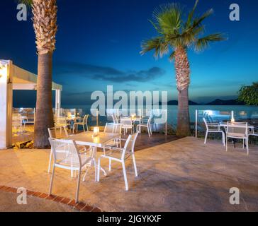 Un bel caffè sulla costa del mare di notte in estate. Sedie e tavoli Foto Stock