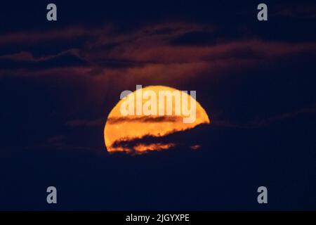 Lauder Moor, Scottish Borders, Regno Unito. 13th luglio 2022. Regno Unito la Supermoon il 13th 2022 luglio sorge attraverso le nubi basse viste da Lauder Moor nei confini scozzesi. Oscar Wilkinson, è rimasto fino a tardi per guardare lo spettacolo della natura. Stasera la luna piena è anche chiamata la luna buck ed è l'unico superman del 2022. Le Superlune sono categorizzate quando la Luna è a 360.000km (o meno) lontano dalla Terra nel suo percorso orbitale. Picture Credit: phil wilkinson/Alamy Live News Foto Stock