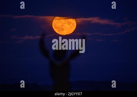 Lauder Moor, Scottish Borders, Regno Unito. 13th luglio 2022. Regno Unito la Supermoon il 13th 2022 luglio sorge attraverso le nubi basse viste da Lauder Moor nei confini scozzesi. Oscar Wilkinson, è rimasto fino a tardi per guardare lo spettacolo della natura. Stasera la luna piena è anche chiamata la luna buck ed è l'unico superman del 2022. Le Superlune sono categorizzate quando la Luna è a 360.000km (o meno) lontano dalla Terra nel suo percorso orbitale. Picture Credit: phil wilkinson/Alamy Live News Foto Stock