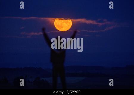 Lauder Moor, Scottish Borders, Regno Unito. 13th luglio 2022. Regno Unito la Supermoon il 13th 2022 luglio sorge attraverso le nubi basse viste da Lauder Moor nei confini scozzesi. Oscar Wilkinson, è rimasto fino a tardi per guardare lo spettacolo della natura. Stasera la luna piena è anche chiamata la luna buck ed è l'unico superman del 2022. Le Superlune sono categorizzate quando la Luna è a 360.000km (o meno) lontano dalla Terra nel suo percorso orbitale. Picture Credit: phil wilkinson/Alamy Live News Foto Stock