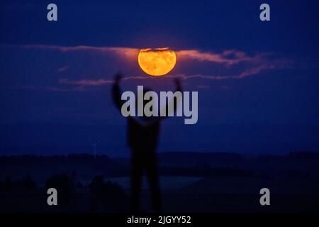 Lauder Moor, Scottish Borders, Regno Unito. 13th luglio 2022. Regno Unito la Supermoon il 13th 2022 luglio sorge attraverso le nubi basse viste da Lauder Moor nei confini scozzesi. Oscar Wilkinson, è rimasto fino a tardi per guardare lo spettacolo della natura. Stasera la luna piena è anche chiamata la luna buck ed è l'unico superman del 2022. Le Superlune sono categorizzate quando la Luna è a 360.000km (o meno) lontano dalla Terra nel suo percorso orbitale. Picture Credit: phil wilkinson/Alamy Live News Foto Stock