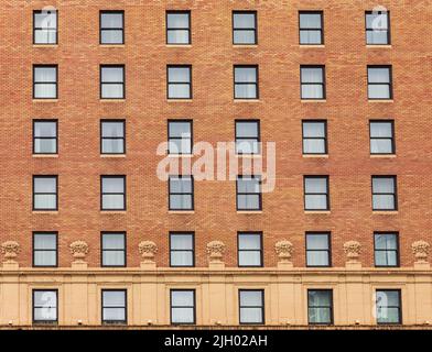 Molte finestre in fila sulla facciata dell'edificio urbano di appartamenti. Edificio in mattoni. Foto di strada, nessuno, fuoco selettivo Foto Stock