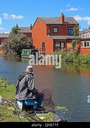 Uomo che pesca sul canale Bridgewater - ramo di Leigh, Wigan, Lancashire, Inghilterra, Regno Unito, WN7 3AE Foto Stock